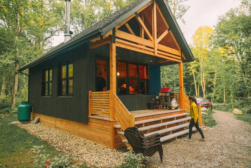 Chalet de location en forêt, cabane à la campagne près du lac pour des vacances en pleine nature. Femme entrant dans sa maison, son chez-soi loin de chez elle.
